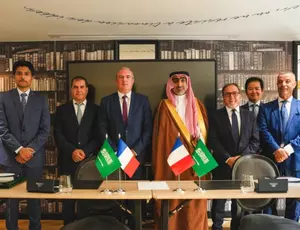 Veolia and Saudi partner representatives gather following the signing of a strategic agreement, with French and Saudi flags displayed.