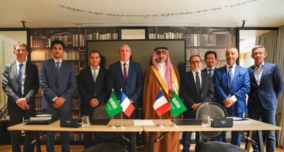 Veolia and Saudi partner representatives gather following the signing of a strategic agreement, with French and Saudi flags displayed.